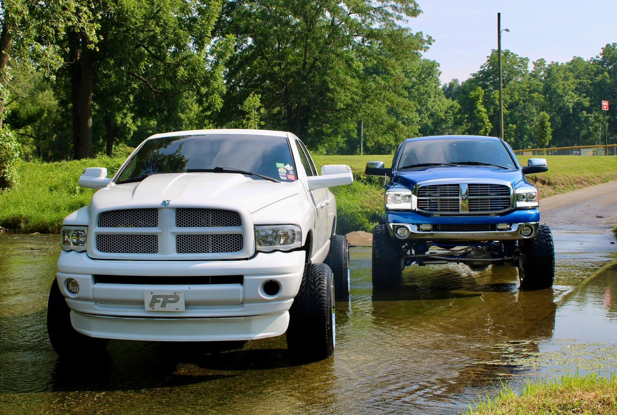 White and blue pickup trucks parked in a shallow creek